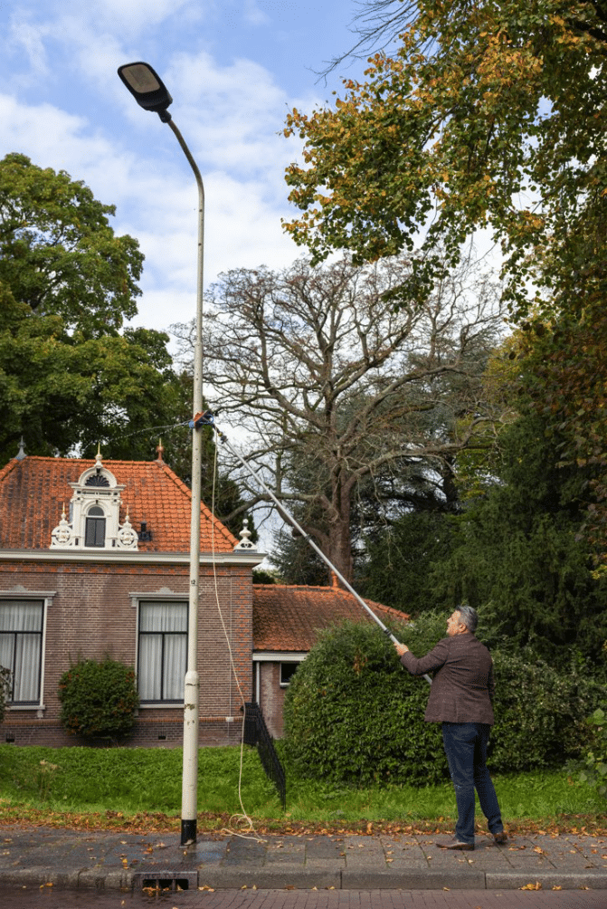 Wethouder Polatli maakt de lichtmast aan de W. de Vries Robbéweg schoon. - Gemeente Gorinchem